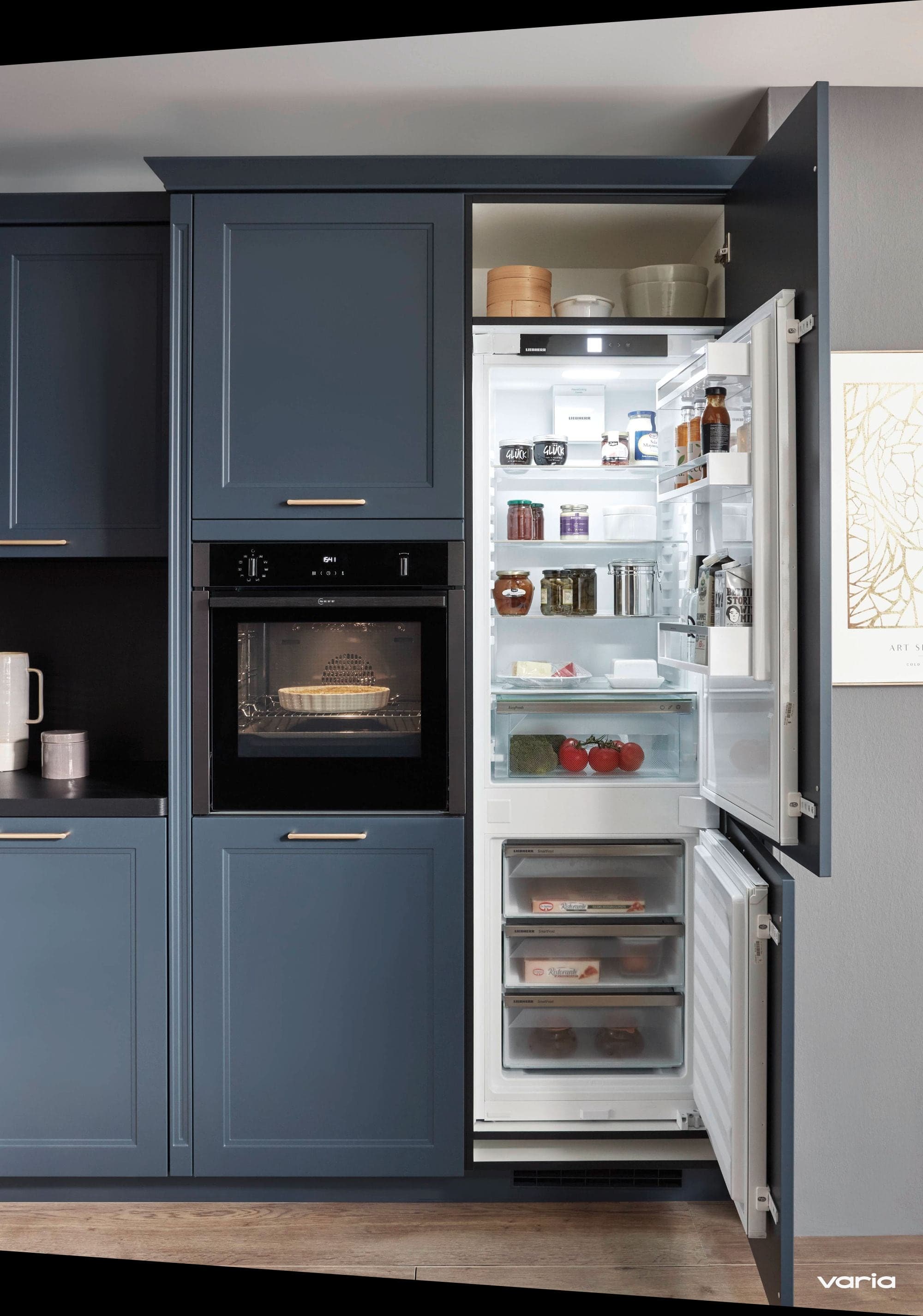 Geöffneter Einbaukühlschrank neben einem Backofen auf Augenhöhe in blauer Landhausküche