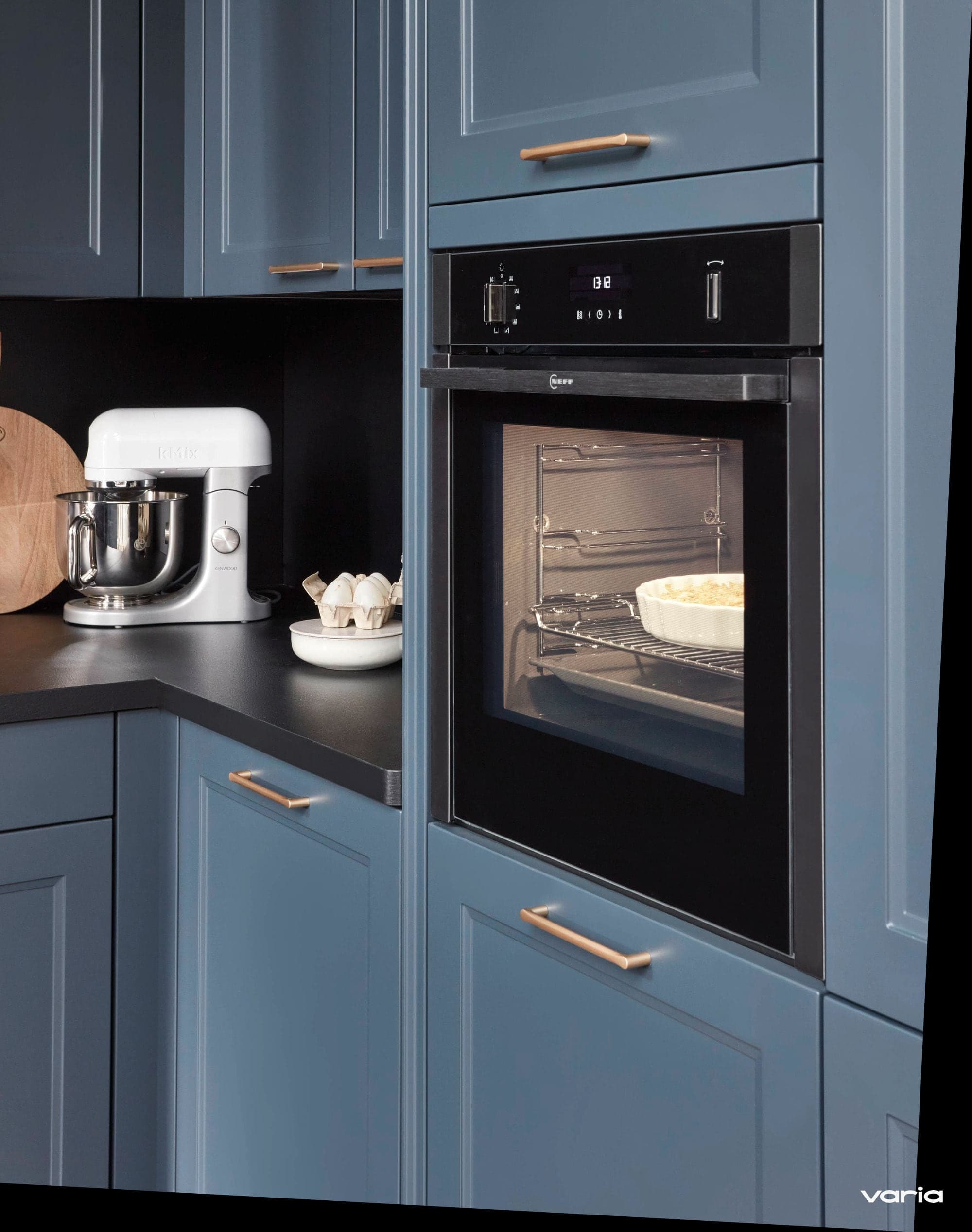 Erhöht eingebauter Backofen in einer blauen Landhausküche, daneben eine Küchenmaschine auf der Arbeitsplatte