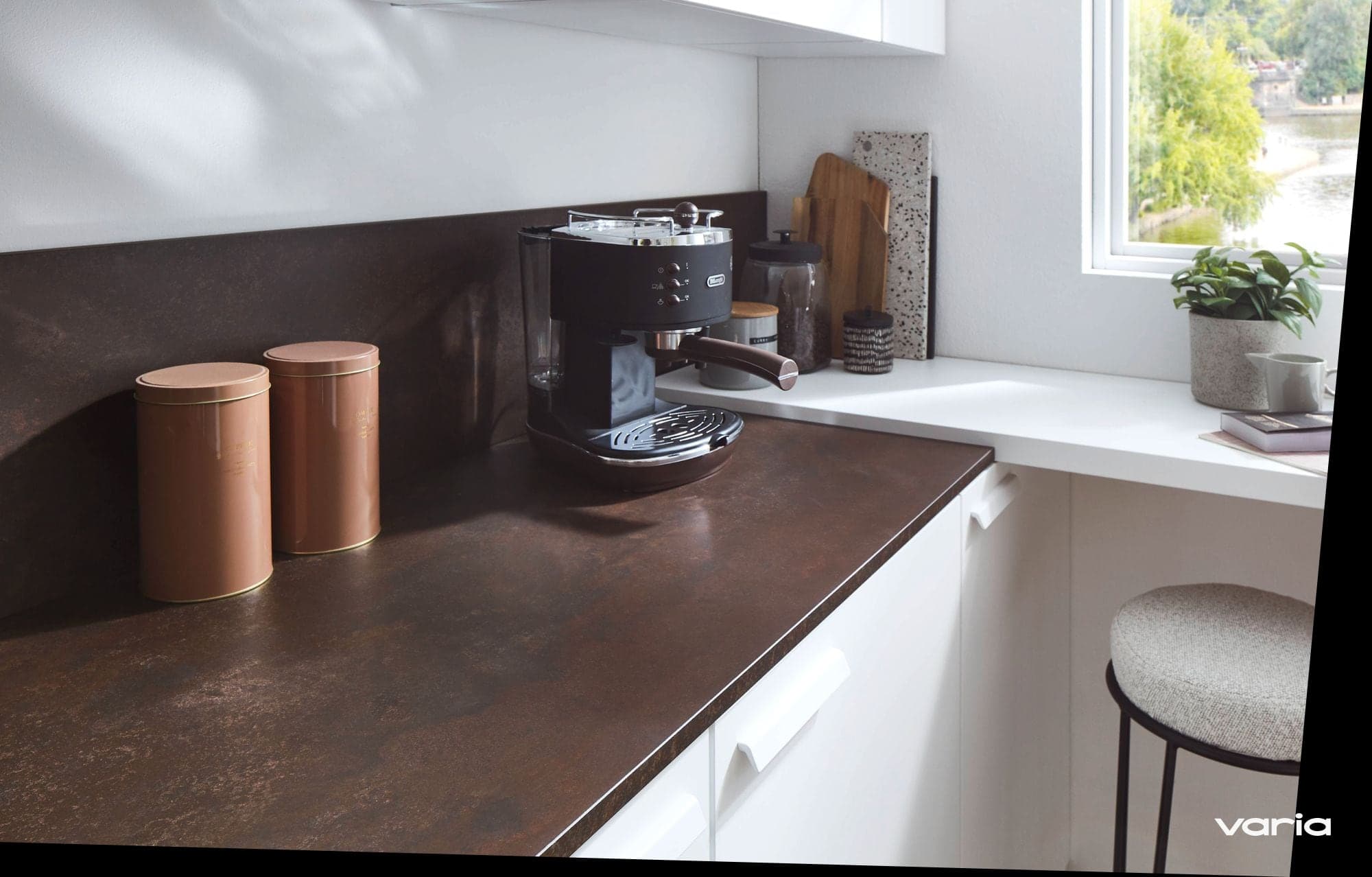 Dunkle Arbeitsplatte mit Kaffeemaschine, an der Wand dahinter zwei Steckdosen über der Platte
