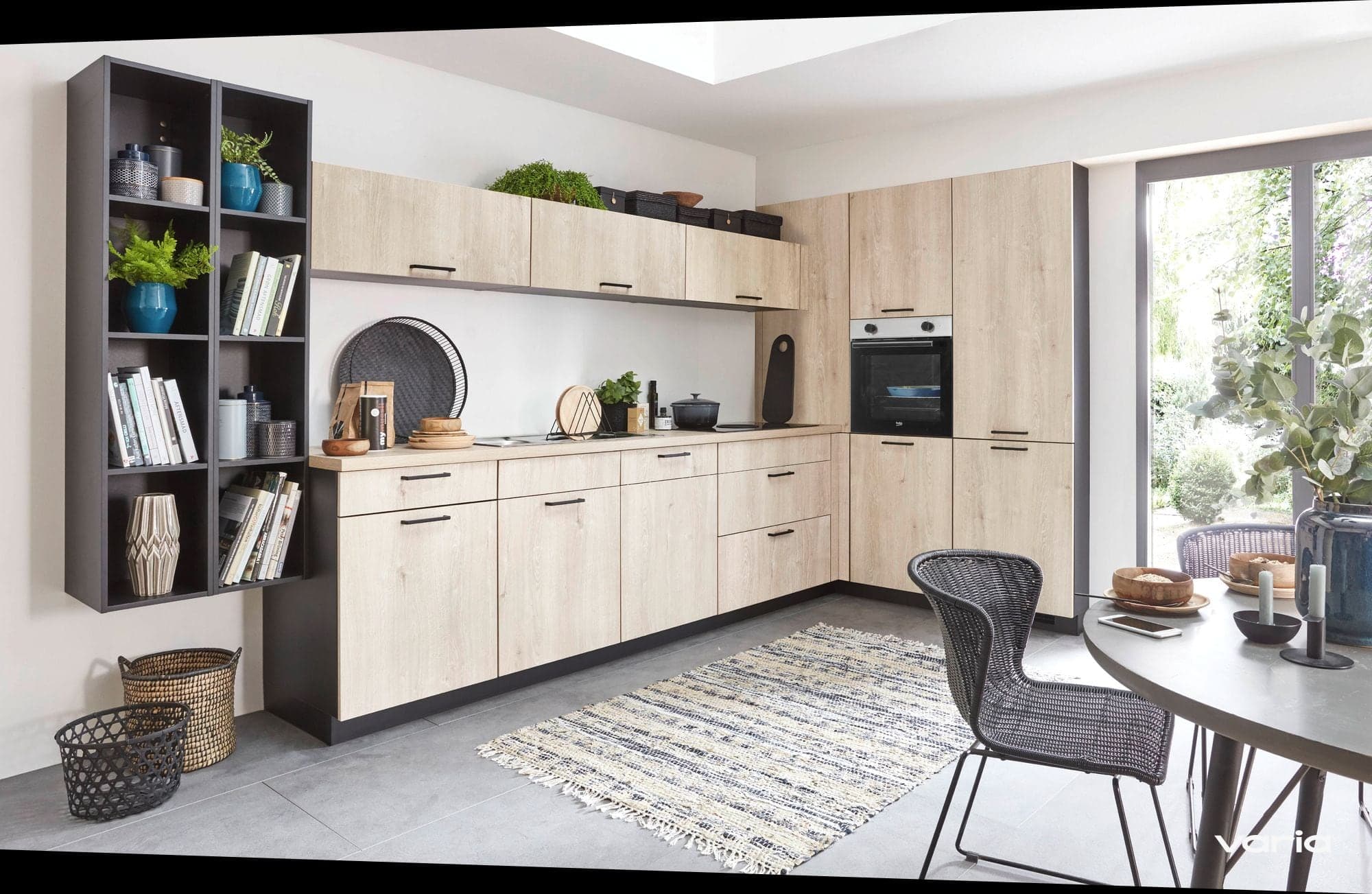 Wohnküche in hellem Holz mit offenem Regal, Teppich und rundem Esstisch