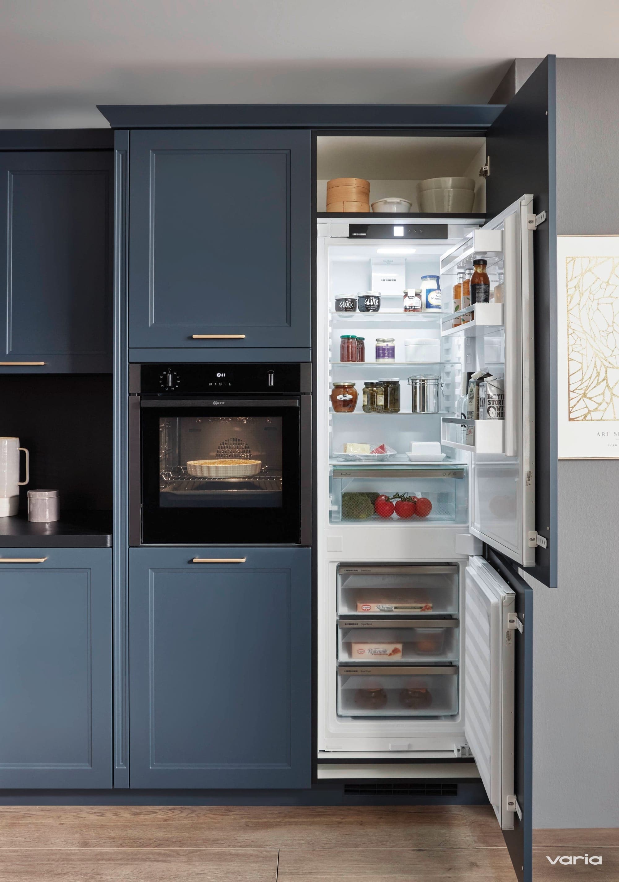 Hochgebauter Backofen und Kühlschrank nebeneinander in einer blauen Purion-Küche