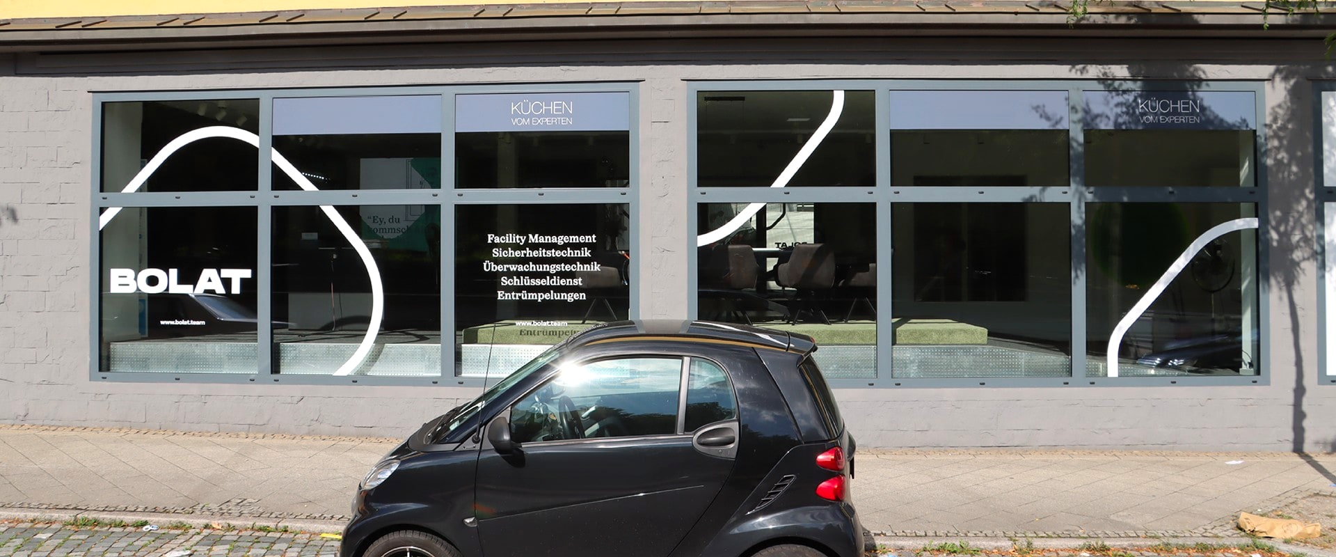 Das Küchenstudio in der Ludwigsburger Innenstadt von der Straße aus: lange Schaufensterfront mit den Schriften von BOLAT und „Küchen vom Experten“, davor ein schwarzer Smart